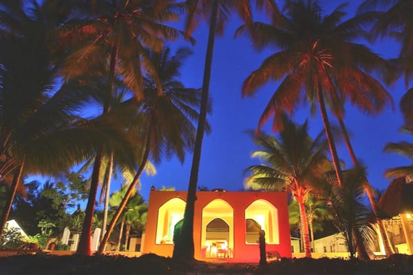 SawaSawa Beach House lit up at night among palm trees