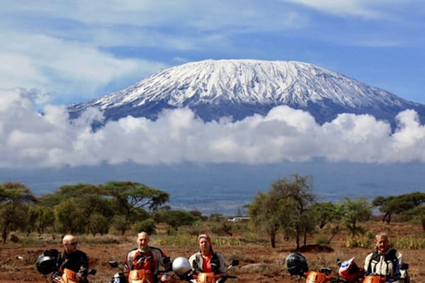 Four riders and their motorcycles in front of Mount Kilimanjaro