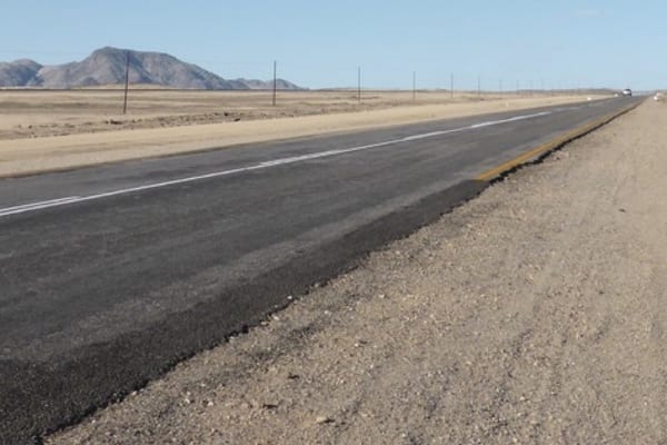 An empty asphalt road through a dry southern African landscape